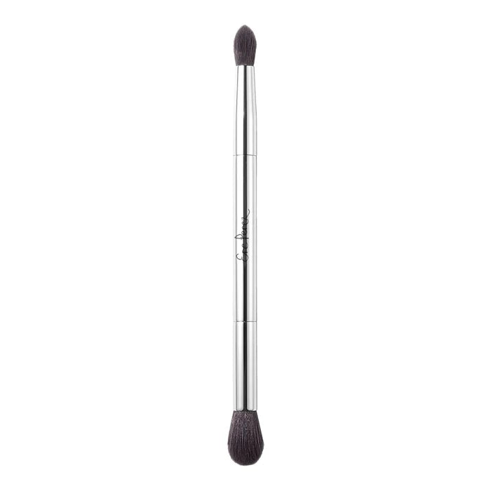 A dual-ended makeup brush with a slim silver metal handle, dark brown bristles on both ends.