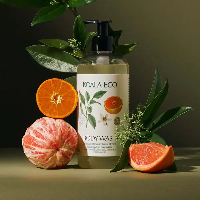 Koala Eco body wash bottle with oranges and grapefruit on a dark background.