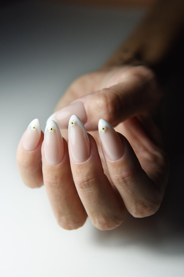White French tip press-on nails with tiny daisies on every nail – detail view