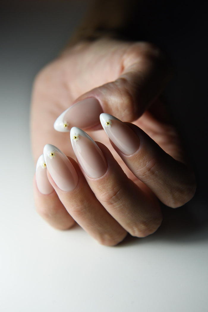 White French tip press-on nails with tiny daisies on every nail – detail view