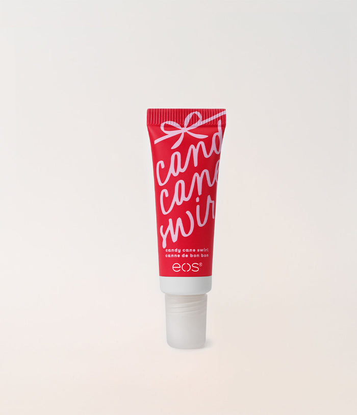 A red squeeze tube of EOS Cosmetics 'Candy Cane Wreath' holiday color corrector, featuring white script lettering and a white cap, set against a clean off-white background.