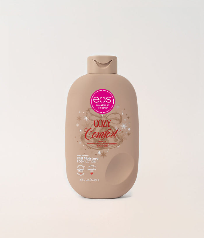 A beige plastic bottle of EOS Cosmetics & Beauty 'Cozy Comfort' body lotion, featuring a pink circular logo and decorative text, set against a clean off-white background.