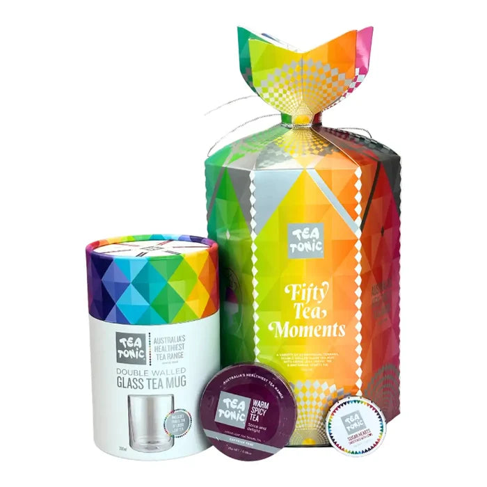 Tea Tonic gift set featuring a large colorful geometric box labeled 'Fifty Tea Moments,' a matching glass tea mug canister, two tea tin lids, and a small round tea tin, all on a white background.