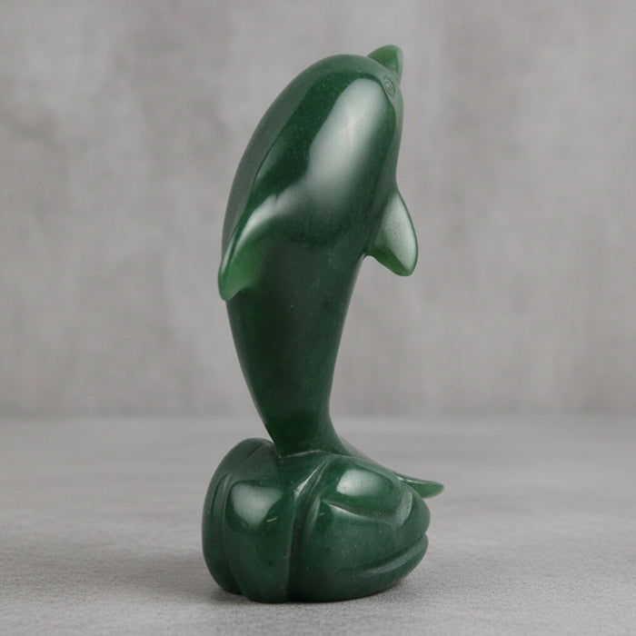 Green jade sculpture of a dolphin on a white background