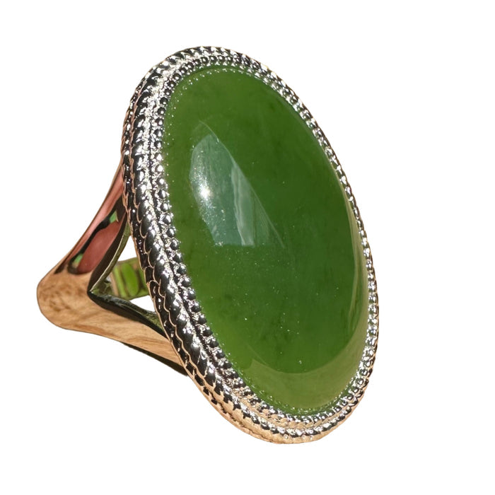 Green jade stone ring with silver setting on a wooden surface