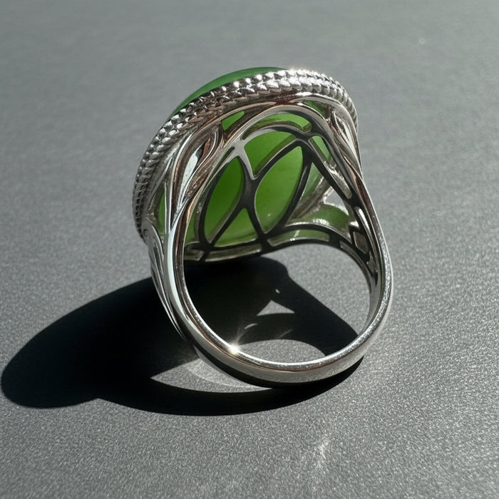 Silver ring with green jade on a wooden surface