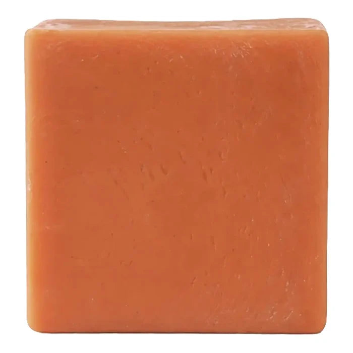 A single square bar of orange soap with a textured surface, isolated on a white background.
