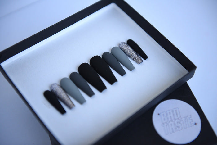 Black and grey matte press-on nails with silver glitter accents
