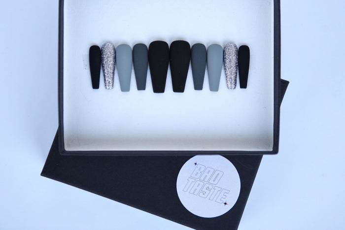 Black and grey matte press-on nails with silver glitter accents – detail view