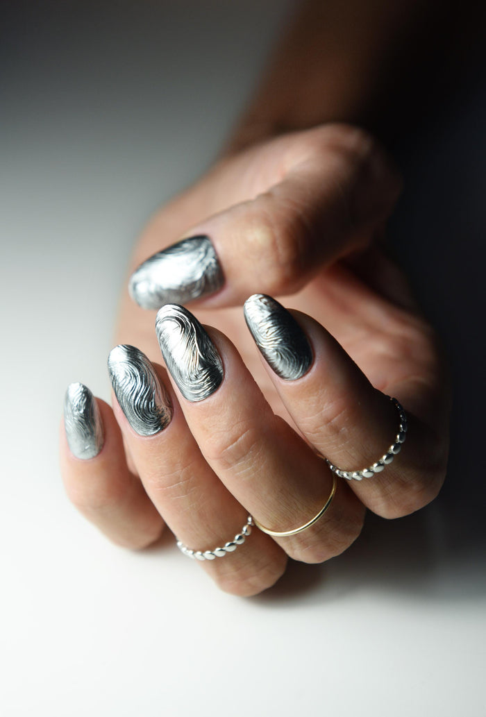 Sculpted silver chrome swirl press-on nails with a molten metal effect
