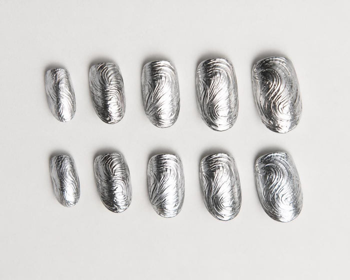 Sculpted silver chrome swirl press-on nails with a molten metal effect – detail view