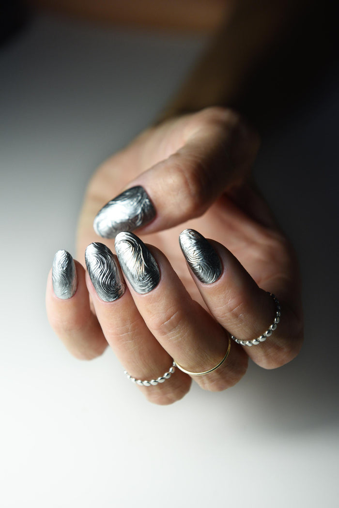 Sculpted silver chrome swirl press-on nails with a molten metal effect – detail view