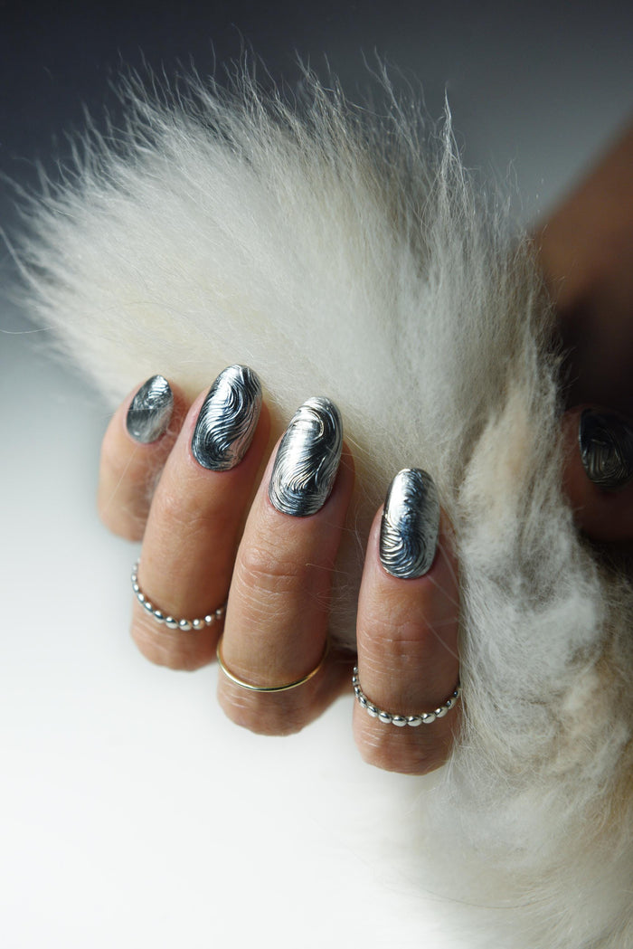 Sculpted silver chrome swirl press-on nails with a molten metal effect – detail view