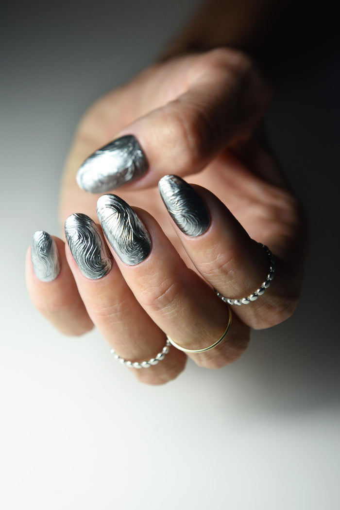 Sculpted silver chrome swirl press-on nails with a molten metal effect – detail view