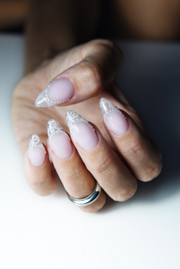 Blush pink press-on nails with white lace French tips and tiny pearls