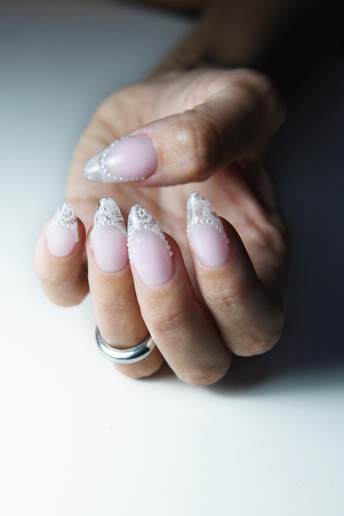 Blush pink press-on nails with white lace French tips and tiny pearls – detail view