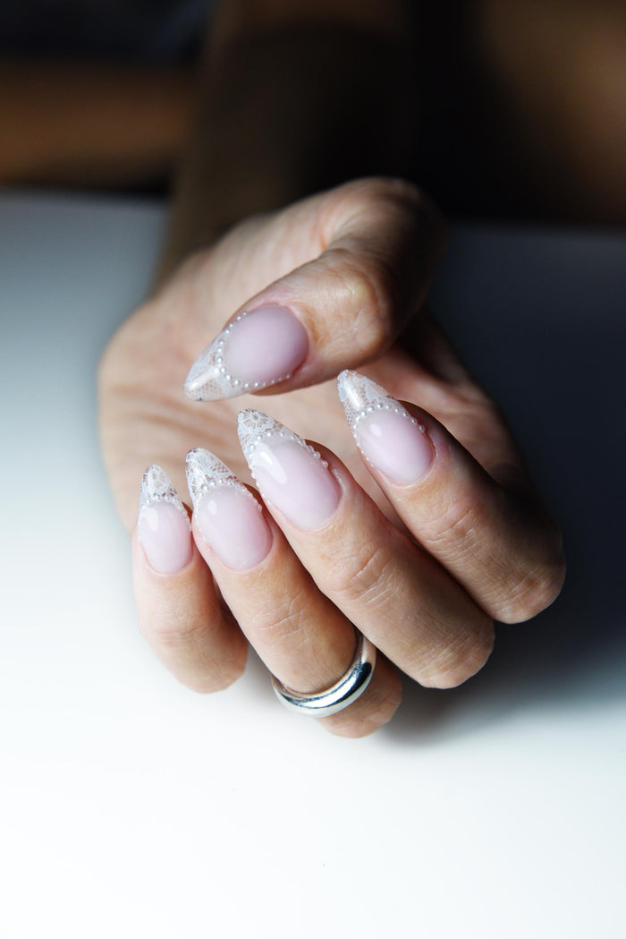 Blush pink press-on nails with white lace French tips and tiny pearls – detail view