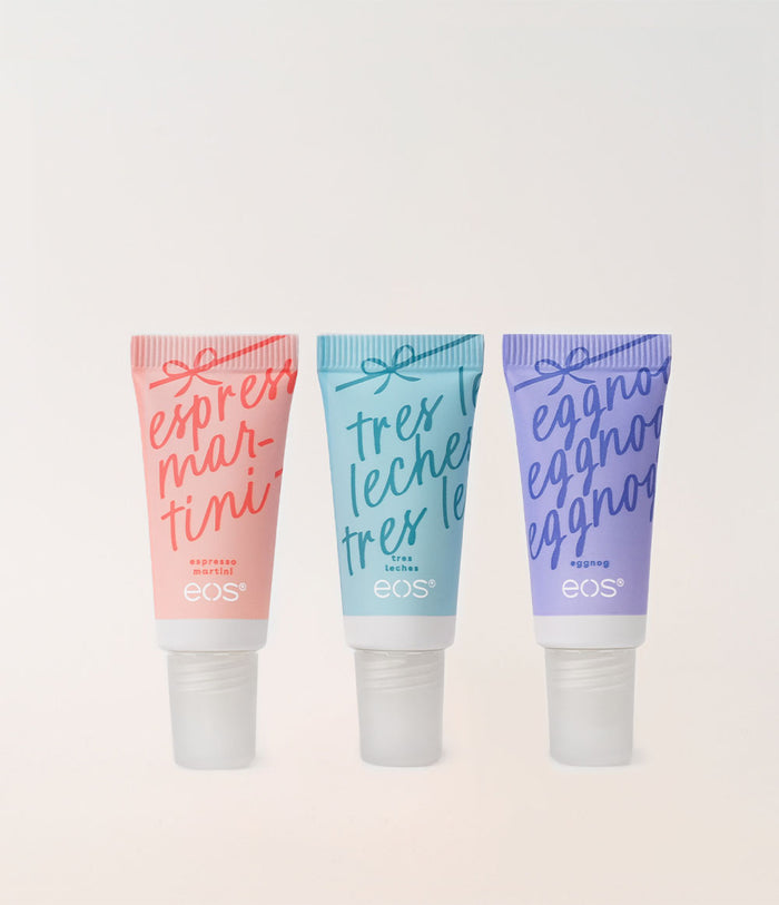 Three EOS skincare tubes in pink, light blue, and lavender purple, lined up horizontally against a clean off-white background. The tubes feature elegant cursive French text and white caps.