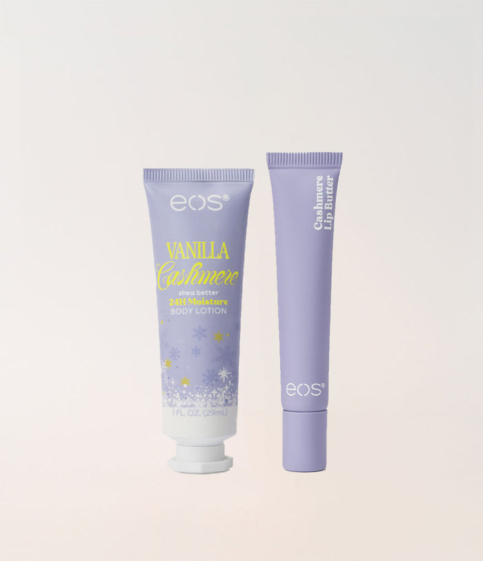 Two EOS cosmetics tubes on a light beige background: a lavender Vanilla Cashmere body lotion tube with yellow and white text and snowflake graphics, and a matching lavender cushion lip butter tube.